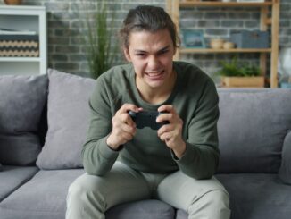 Young man intensely playing video games on couch