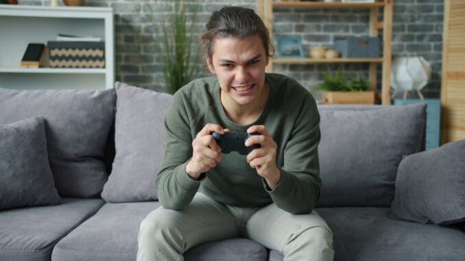 Young man intensely playing video games on couch