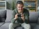 Young man intensely playing video games on couch