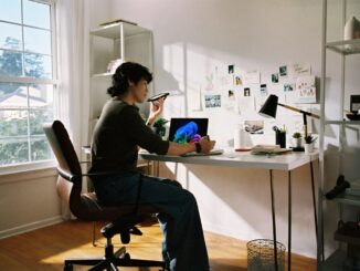 Person working at desk with laptop and phone.