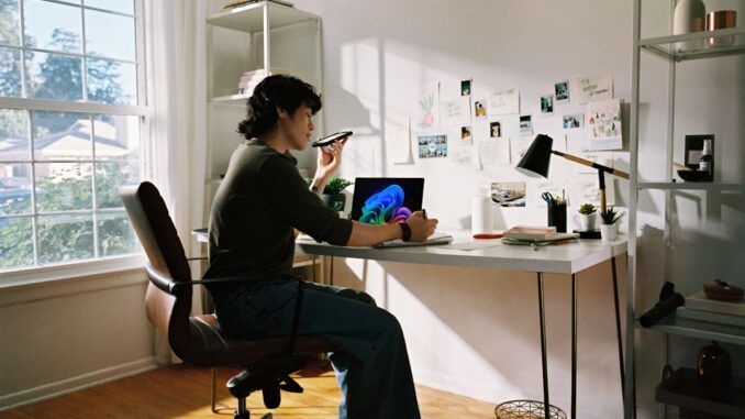 Person working at desk with laptop and phone.