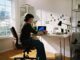 Person working at desk with laptop and phone.