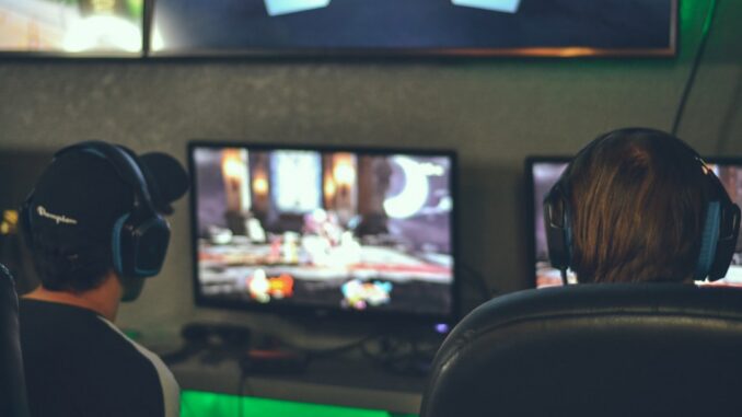 selective focus photography of two persons playing game in front of monitors
