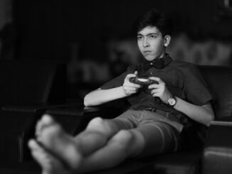 man in black button up shirt and black shorts sitting on chair