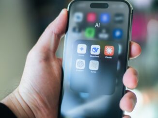 A hand holds a smartphone with various apps.