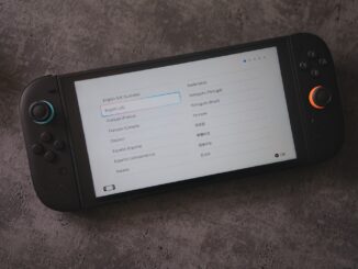 A handheld console displays language options.