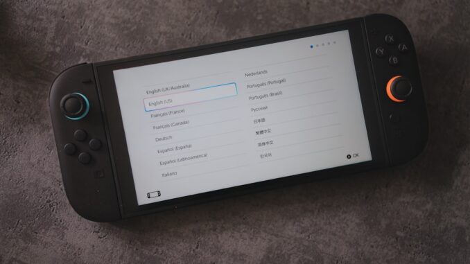 A handheld console displays language options.