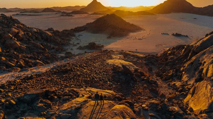the sun is setting over a desert landscape