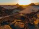 the sun is setting over a desert landscape