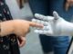 a person holding a robotic hand in front of a mirror