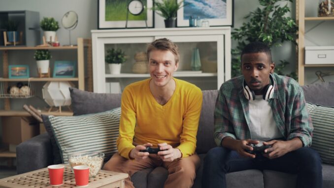 two men sitting on a couch playing video games