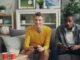 two men sitting on a couch playing video games