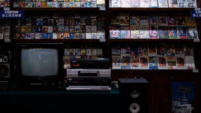 a television sitting on top of a table in front of a book shelf
