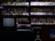 a television sitting on top of a table in front of a book shelf